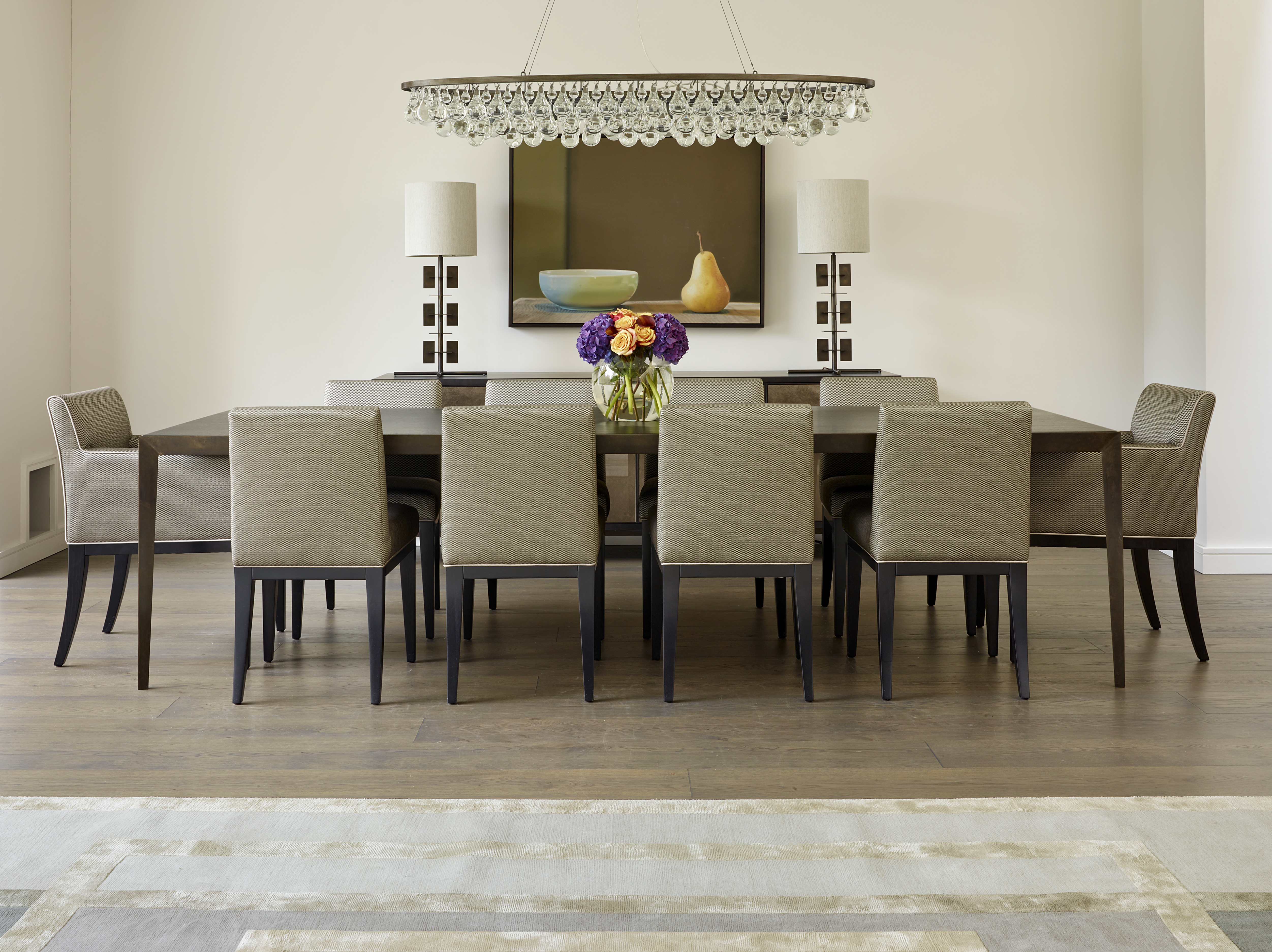Smoked oak dining table with bronze frame with upholstered dining chairs and Ochre pear drop glass chandelier.