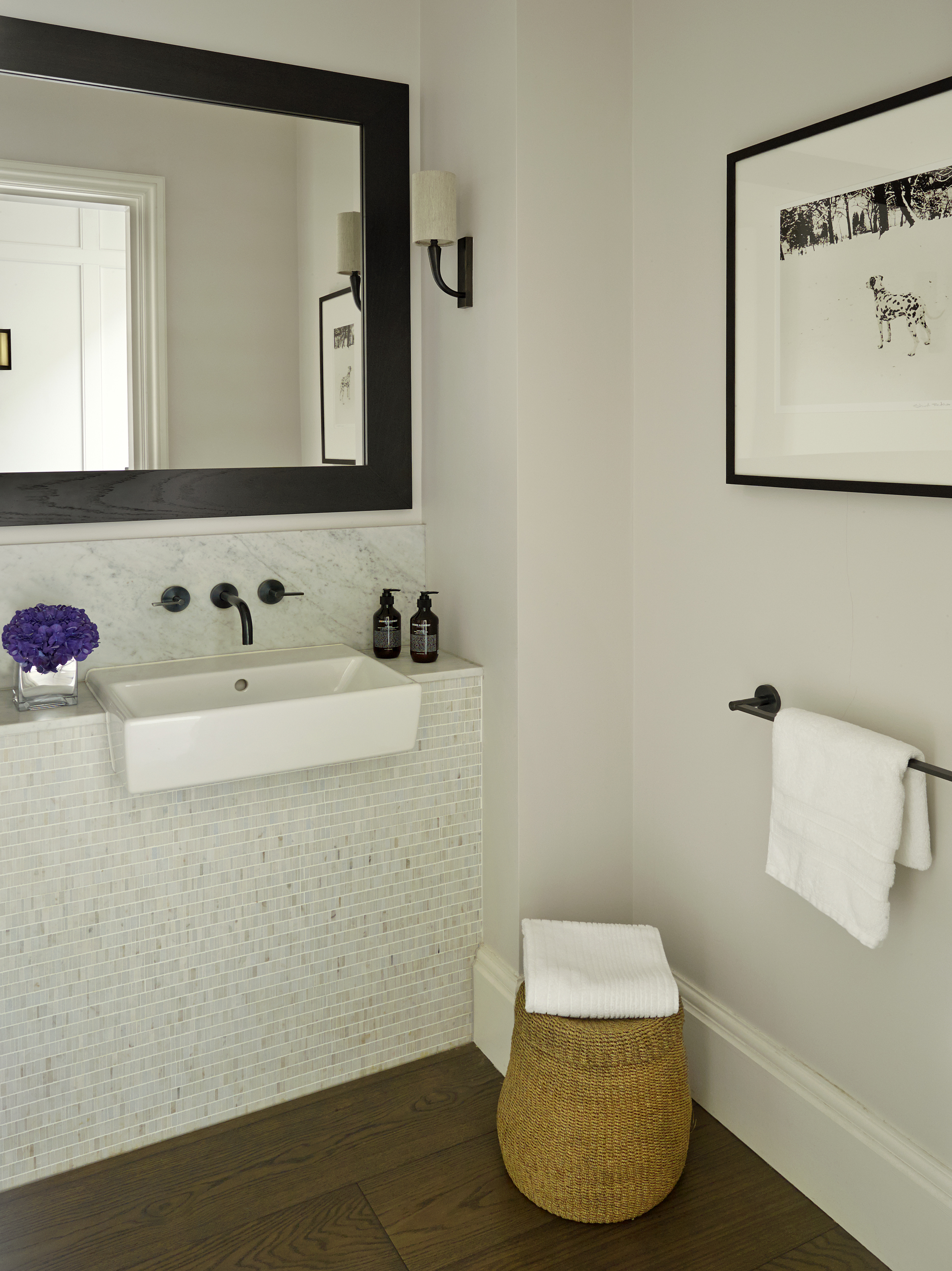 Elegant cloakroom with Carrera marble mosaic tiles, smoked oak flooring and bronze taps and wall lights.