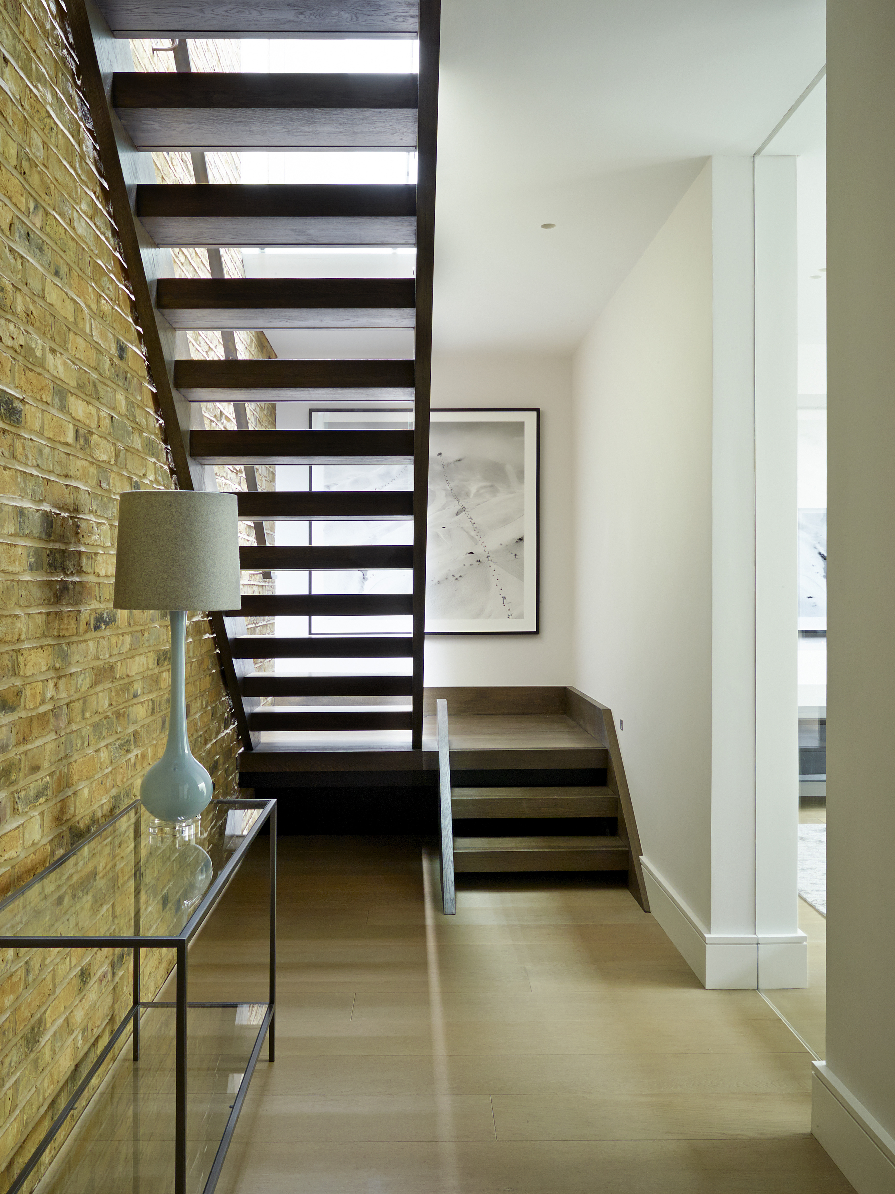 Basement hallway with exposed brickwork and open tread stair design in dark smoked oak.